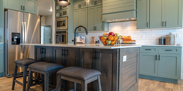 Kitchen With Green Cabinets, Island and Three Stools