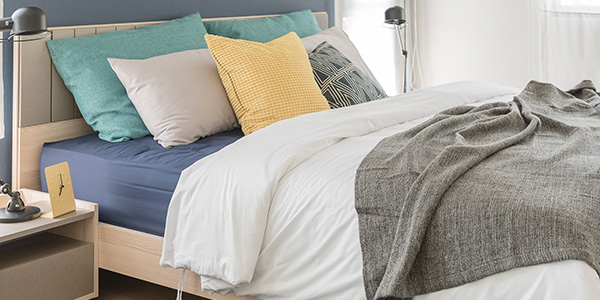 Freshly Made Bed With Blue Sheets and Colorful Pillows