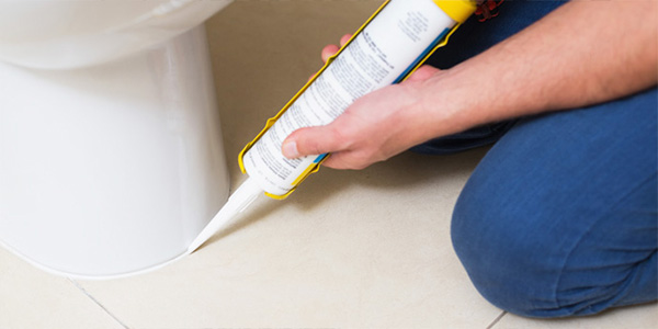 Homeowner Applying Sealant to Toilet Base