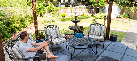 Man Sitting Under Pergola in Backyard