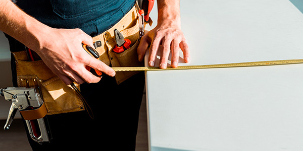 Worker With Tool Belt Using Tape Measure