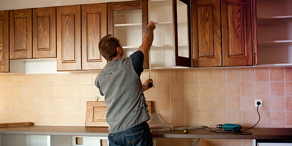 Man Measuring Cabinets in Renovated Kitchen