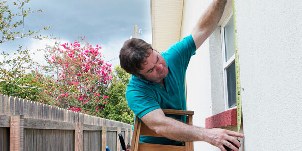 Image of a Man Measuring Windows for Storm Shutters