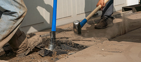 Men Using Pry Bar and Sledgehammer to Break Concrete