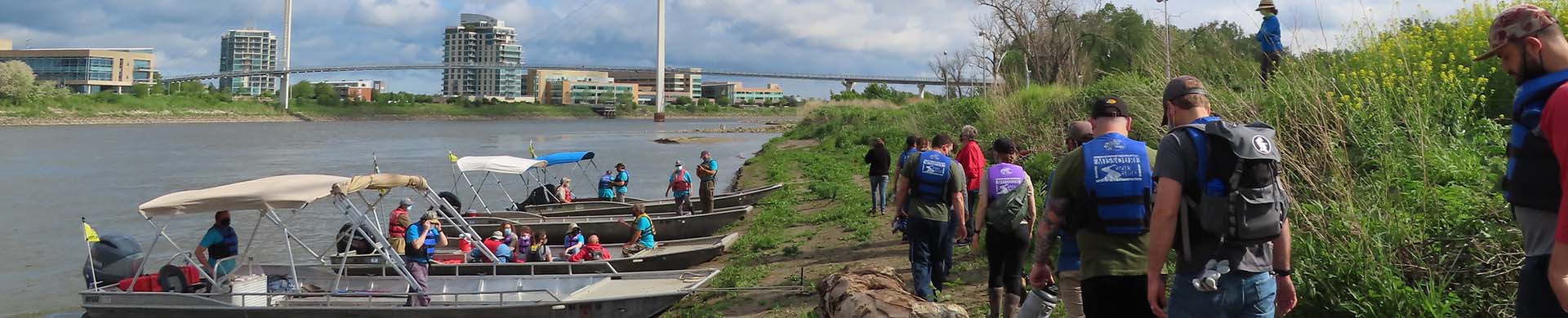 Volunteers on River Bank Next to Boats