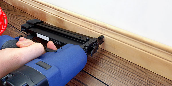 Carpenter Using Nail Gun on Baseboard