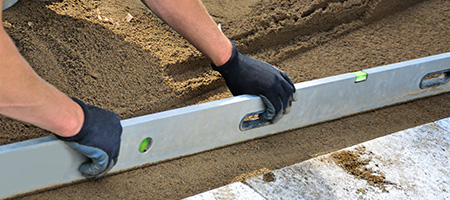 Worker in Gloves Checking Patio Area With a Level