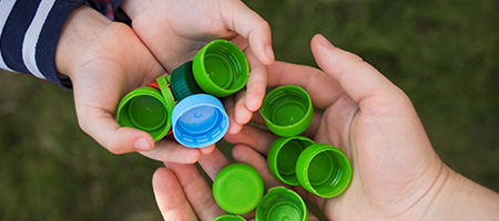 Hands Holding Assorted Plastic Bottle Caps