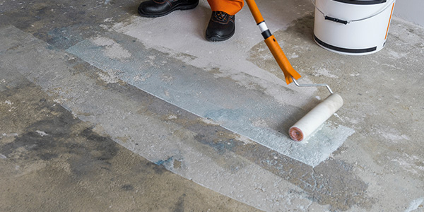 Worker Priming Garage Floor With Roller