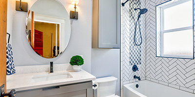 White Tiled Bathroom With Blue Accents and Oval Mirror