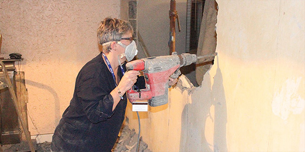 Woman Using Reciprocating Saw to Remove Wall