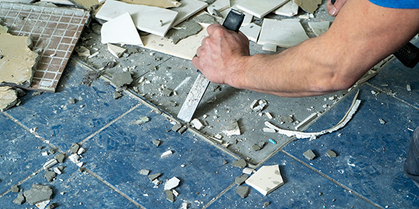 Person Removing Blue Tile With Chisel and Hammer