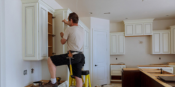 Man Removing Upper White Kitchen Cabinets