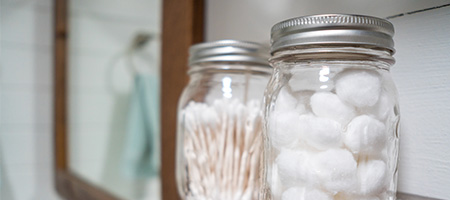 Using Glass Jars Inside a Medicine Cabinet to Hold Cotton Balls and Other Toiletries