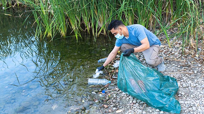 Person Picking Trash Out of Water