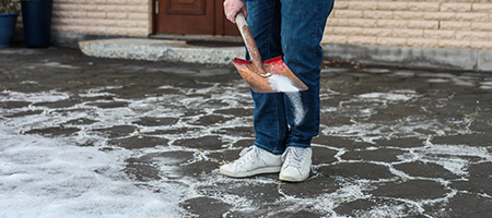 Person Using Shovel to Spread Rock Salt on Sidewalk
