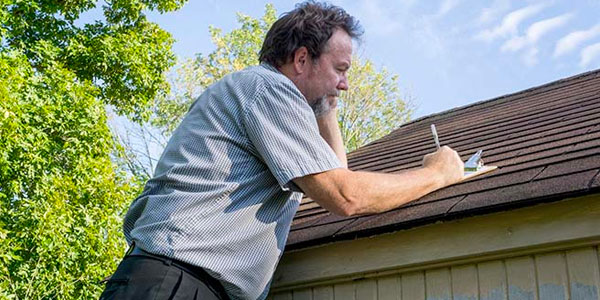Man With Clipboard Inspecting Roof