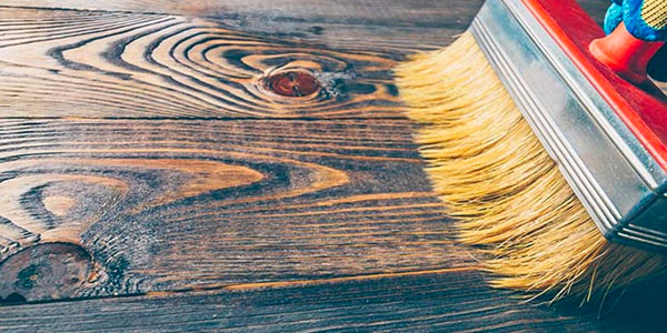 Paintbrush Applying Oil To Dark Hardwood Floor