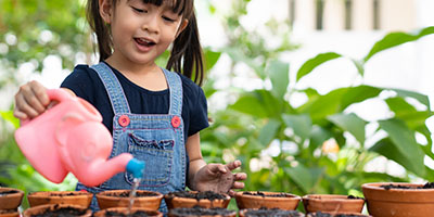 Girl Watering Plant With Watering Can