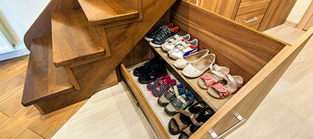 Shoes and Sandals Stored in Pullout Storage Drawer Built Into Side of Staircase.