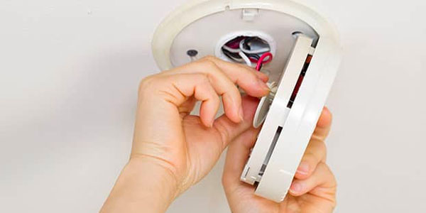 Two Hands Performing Maintenance on Smoke Detector