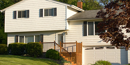 Exterior View of Split-level House With-Low Sloping Roof and Vinyl Siding.