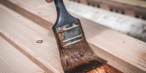 Person Staining Deck With Paintbrush