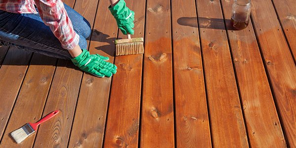 Woman Wearing Gloves to Stain Wood Deck Boards