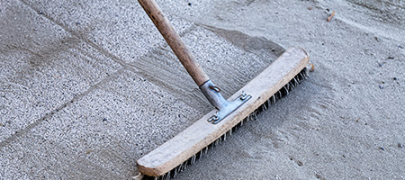 Broom Sweeping Sand Over the Cracks of Patio Paver