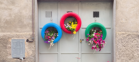 Three Painted Tires Hanging With Flowers