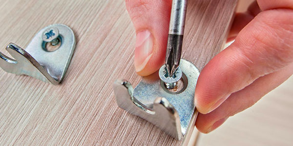 Man Unscrewing Fasteners From Couch Frame