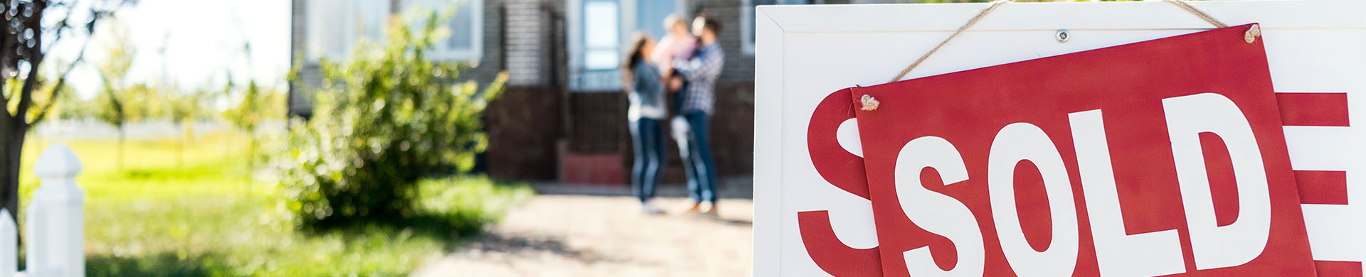 Family in Front of New Home with Sold Sign