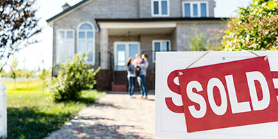 Family in Front of New Home with Sold Sign