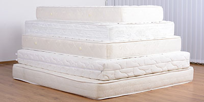 Pile of White Mattresses on Wood Floor