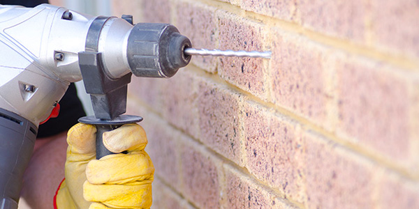 Person Drilling Into a Brick Wall