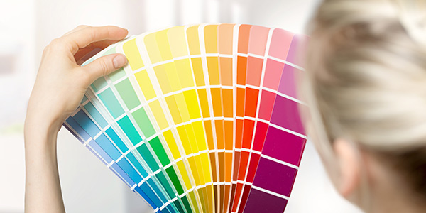 Woman Holding Up a Rainbow of Paint Color Swatches