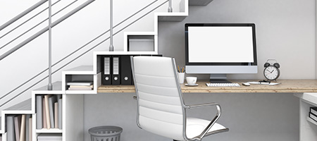 Work Area with Desk, Computer, Chair and Small Bookshelves Built Into the Space Under a Staircase.