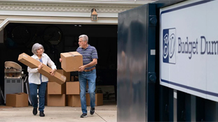 Couple Carrying Boxes to a Roll Off Dumpster