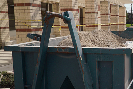 A roll off dumpster filled with rubble and other concrete. 