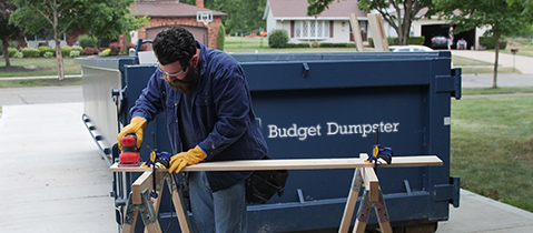 Contractor Working in Front of a Blue Budget Dumpster