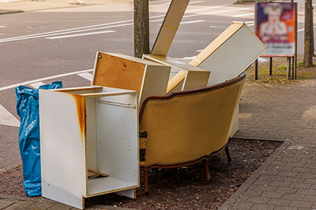 Old Furniture and Bag Sitting on the Curb
