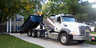 Roll Off Truck Delivering Roll Off Dumpster in Driveway
