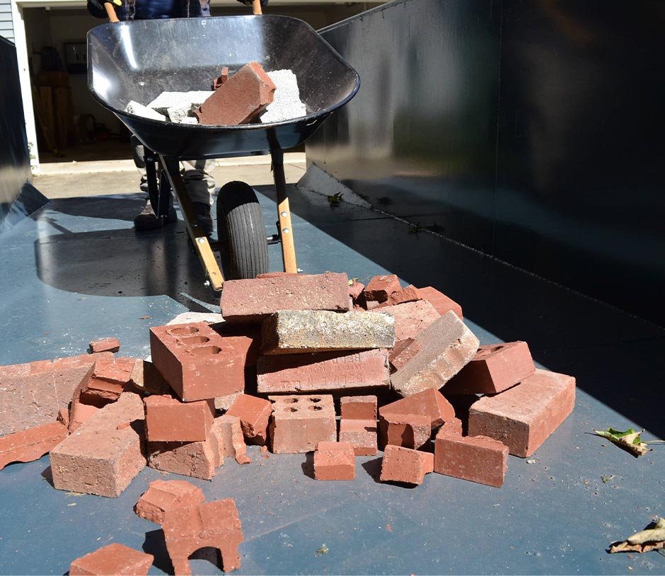 Bricks Being Loaded Into Dumpster By Wheelbarrow