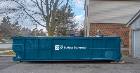 Full Blue Dumpster Parked in Driveway
