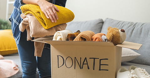 Man Putting Blankets and Clothes Into a Donation Box