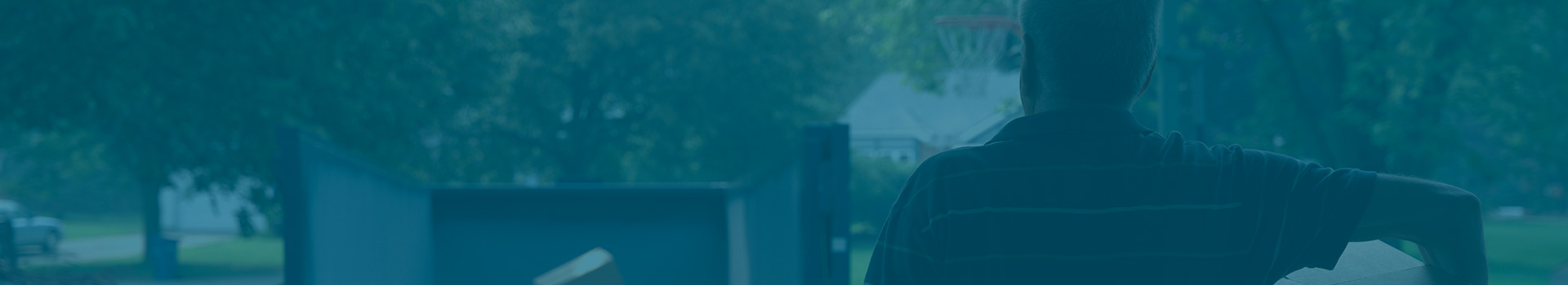 Man Looking at Dumpster in a Driveway