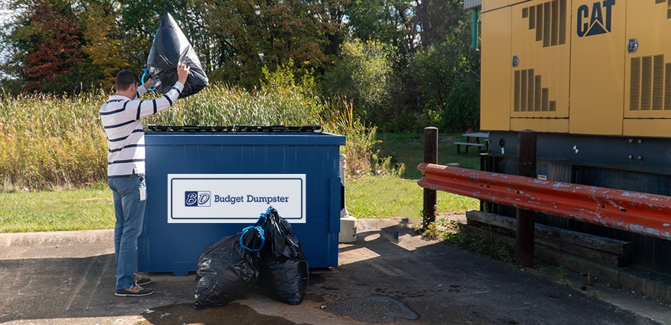 Man Tossing Trash Bags Into a Blue Dumpster