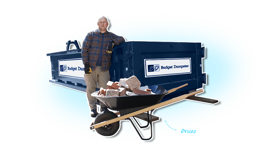 Worker With Wheelbarrow Filled With Debris in Front of Blue Dumpster With Budget Dumpster Logo