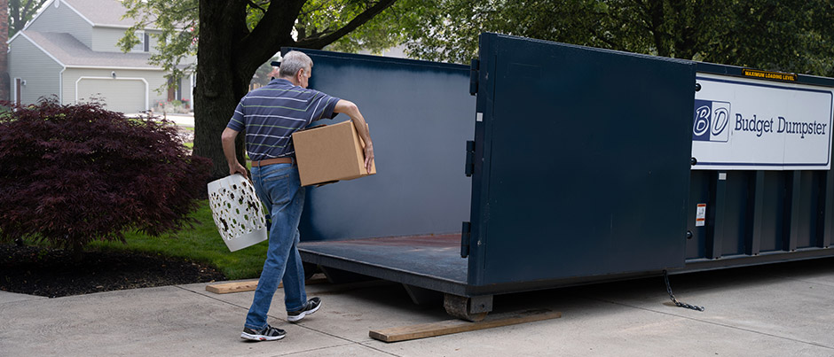 Man Carrying Household Debris Into a Dumpster