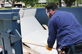 Worker Loads Debris Into Dumpster Through Open Door